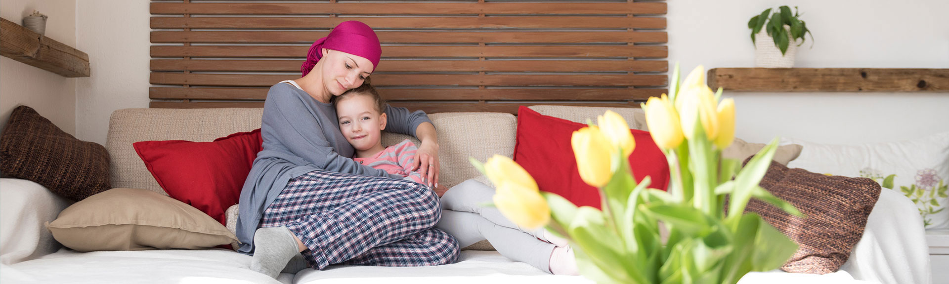 mother with scarf on head cuddling daughter